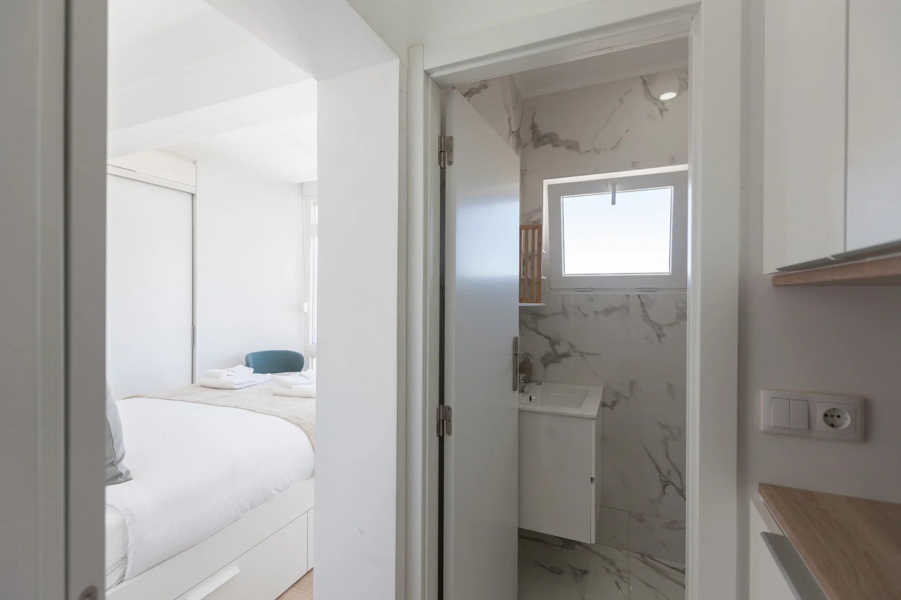 A bright bedroom and adjoining bathroom are visible through open doorways.