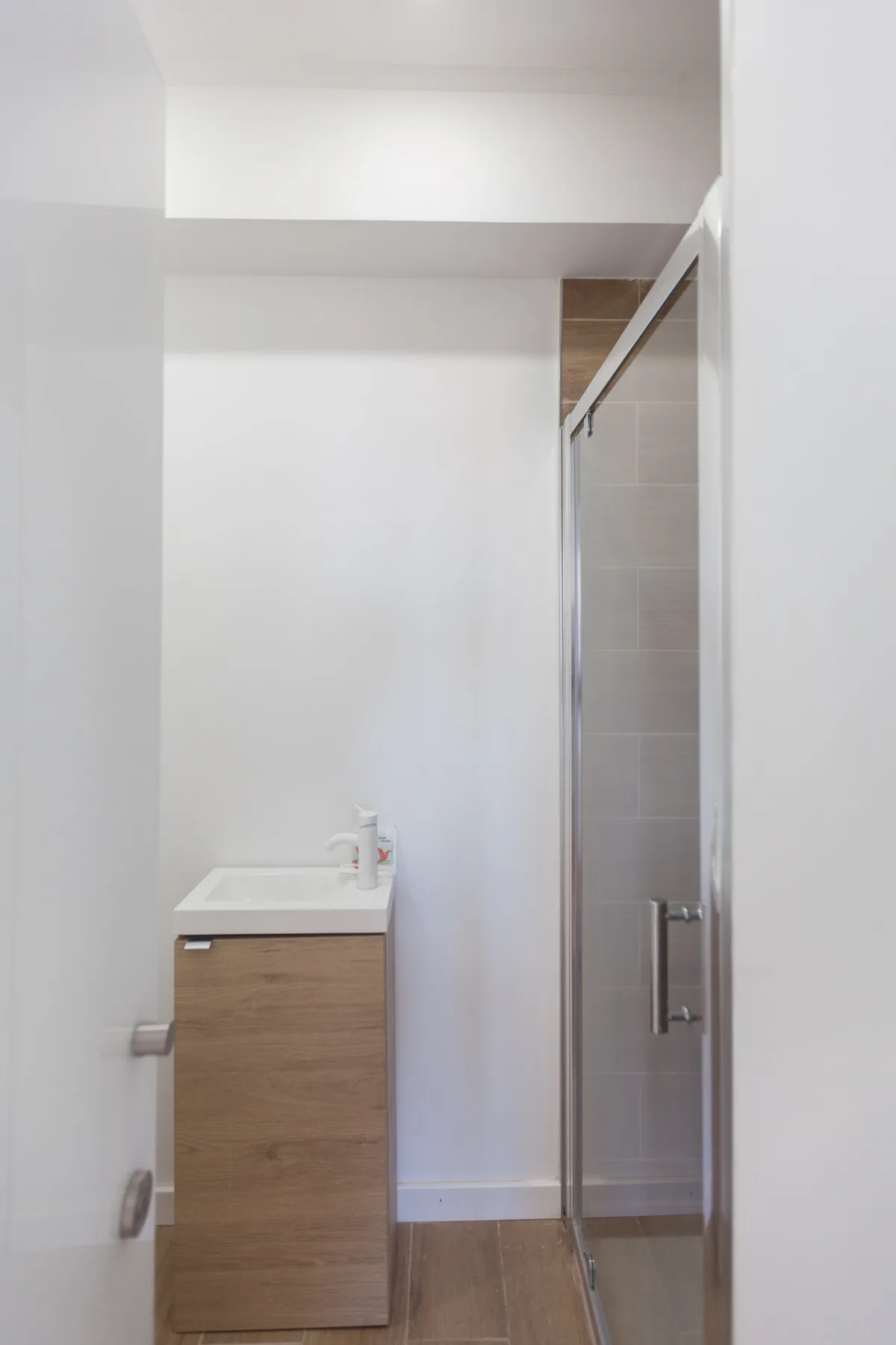 A bathroom with a wood-front vanity and a glass shower enclosure.