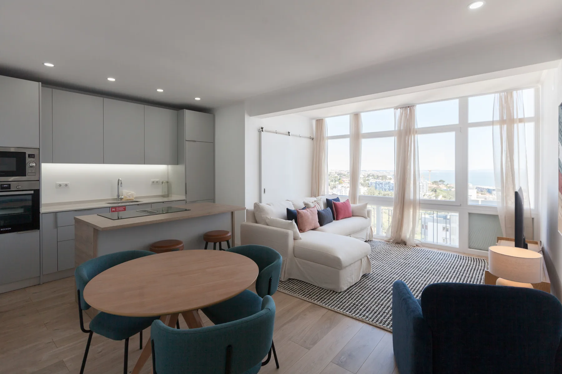 An open-plan living and dining area with a kitchen and large windows.