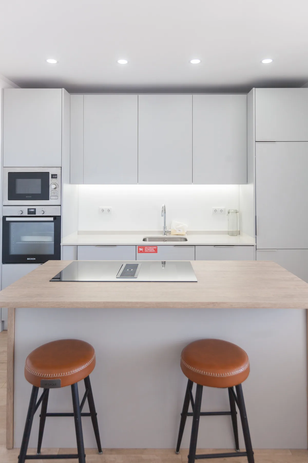 A modern kitchen with a wide counter and two stools.