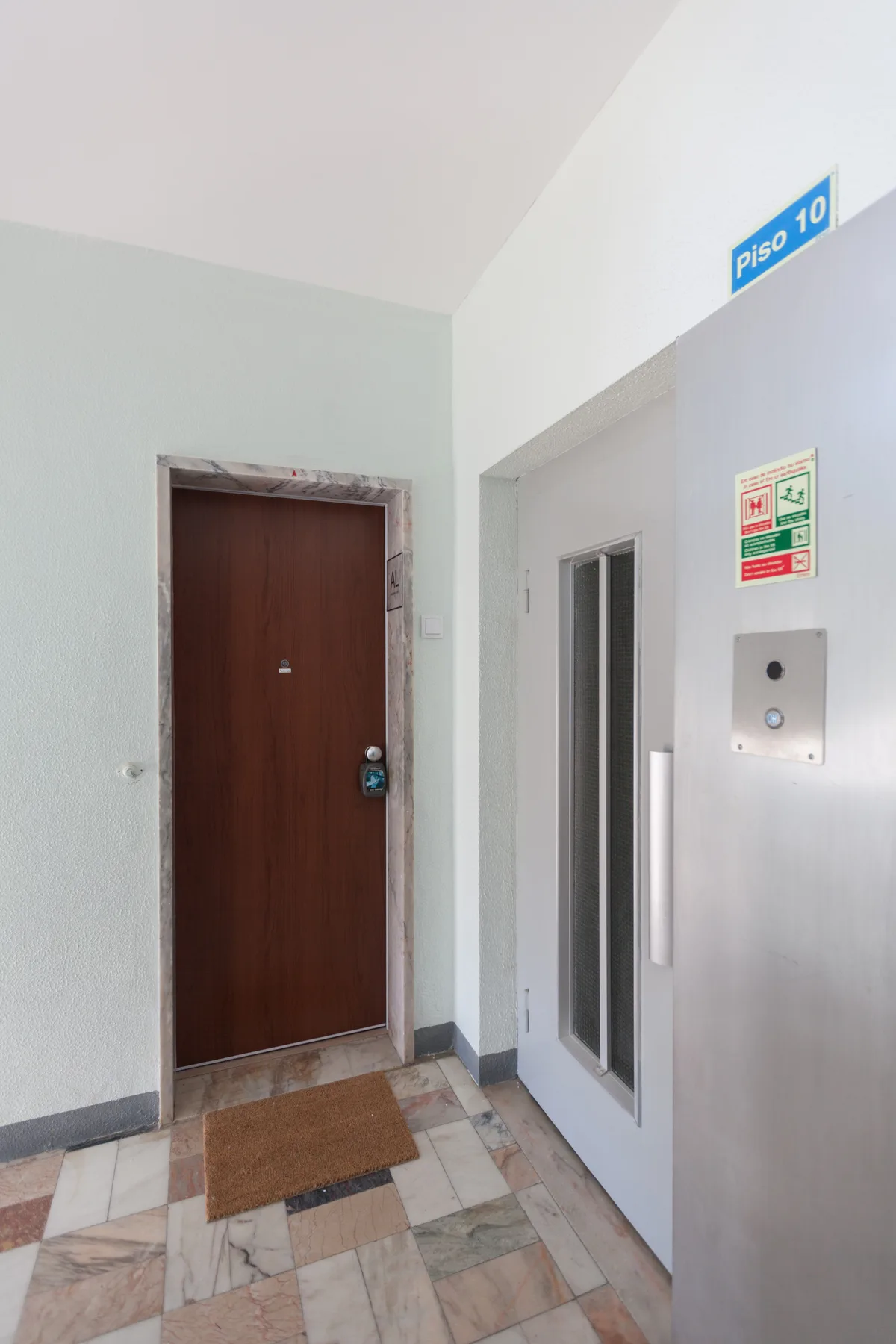An apartment hallway with a brown door beside an elevator.