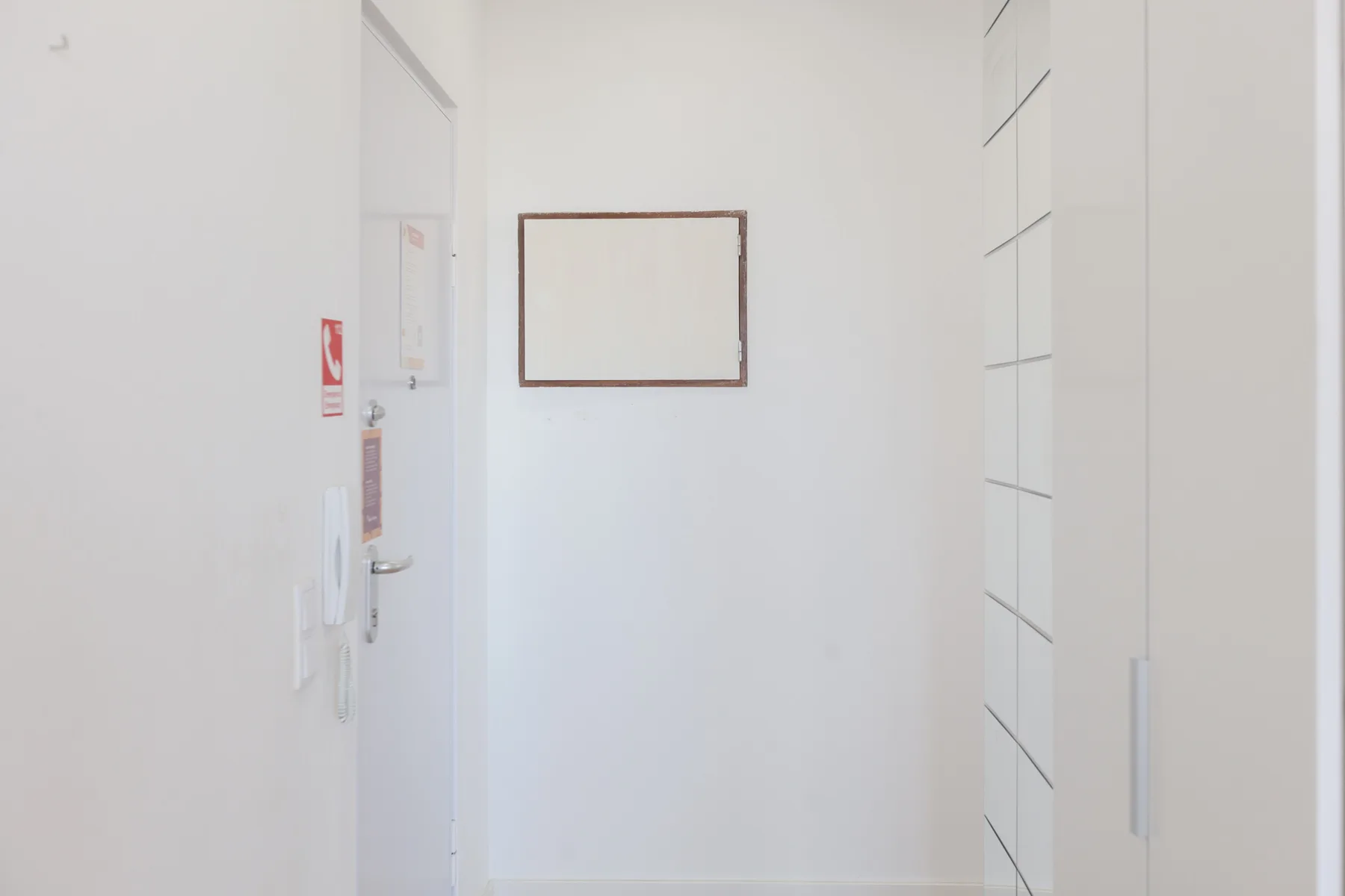 A bright white entry hallway with a door and built-in cabinets.