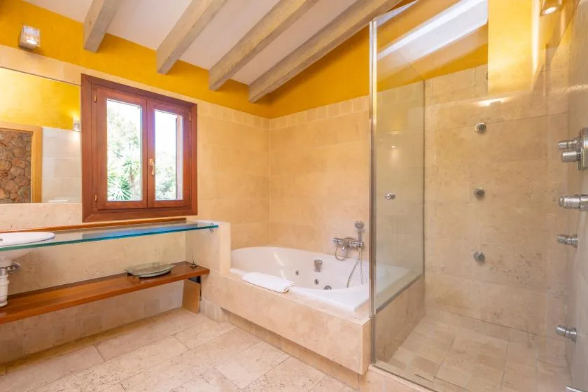 A bathroom with a bathtub, glass shower, and window.