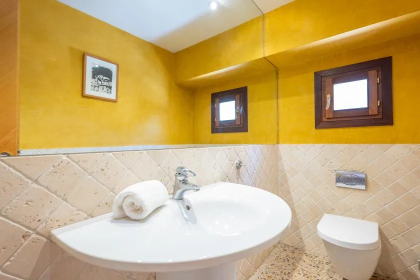 A bathroom with a white sink and toilet beneath yellow walls.