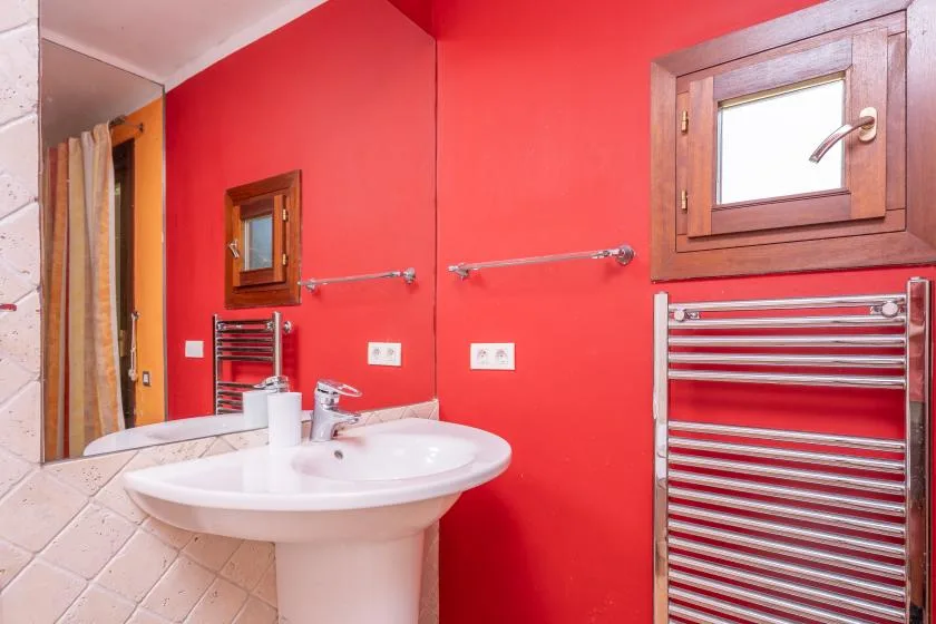 A bathroom with a white sink, red walls, and a metal towel warmer.