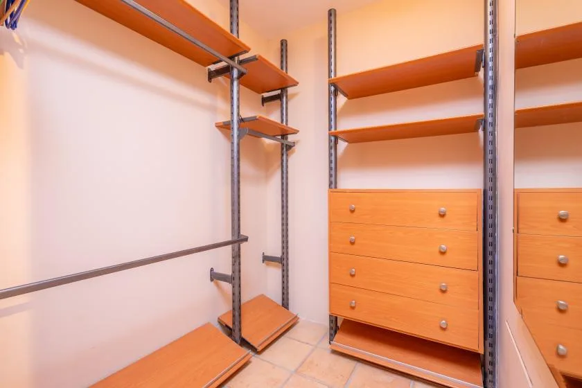A walk-in closet with open shelving, drawers, and hanging rails.
