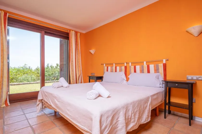 A bedroom with a large bed and a glass door opening onto greenery.