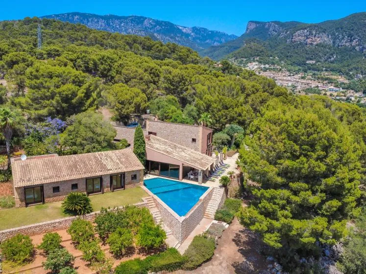 A hillside property with a swimming pool sits among wooded slopes and mountain scenery.