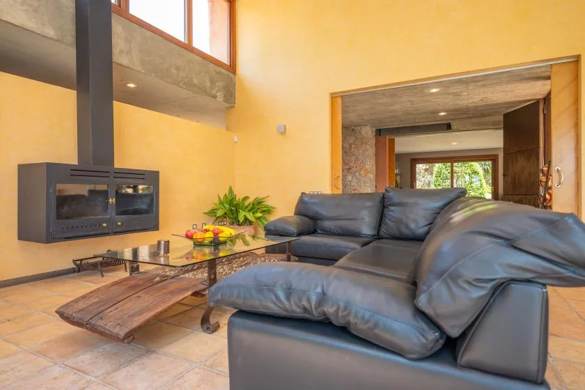 A living room with leather seating, a low table, and a wall-mounted fireplace.