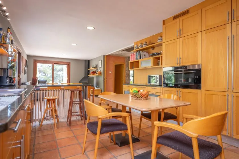 A kitchen and dining area with wooden cabinets, a table, and chairs.