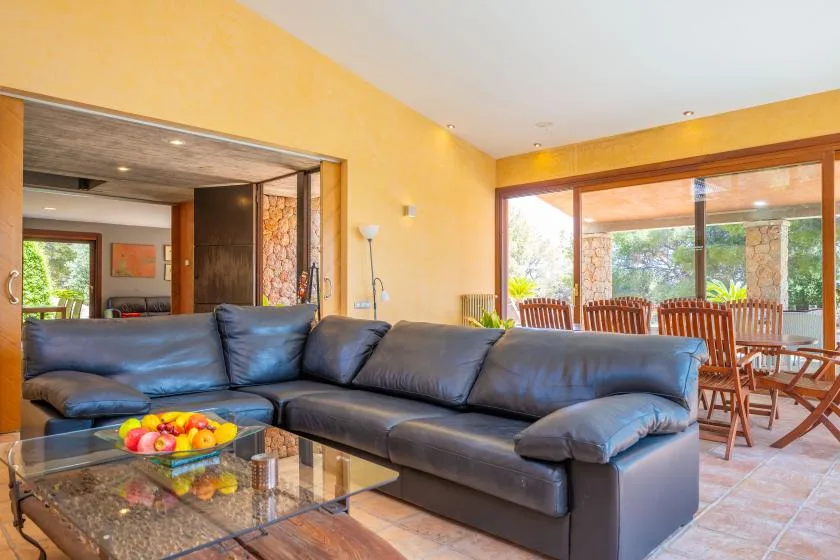 A living room with a dark sectional sofa and glass coffee table beside a dining area.