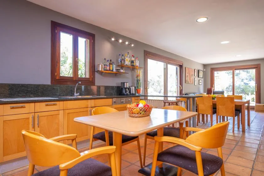 A dining area with a wooden table and chairs beside a kitchen counter.
