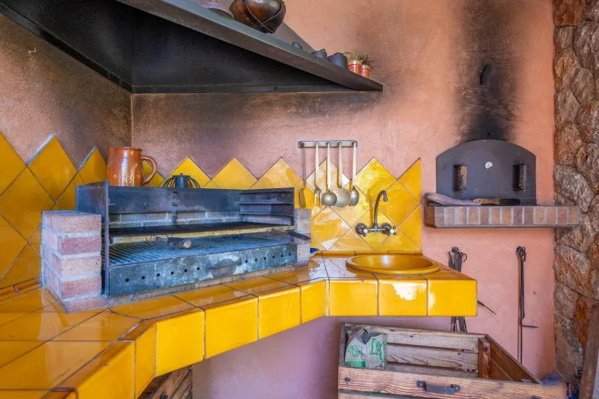 A rustic kitchen with a tiled counter, cooking range, and built-in oven.