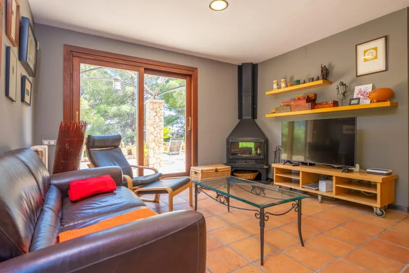 A living room with seating, a television, and a wood-burning stove.