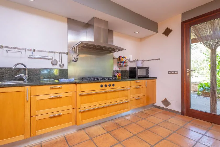 A kitchen with wooden cabinets, a cooktop, and a stainless steel range hood.