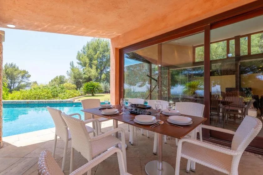 An outdoor dining area beside a swimming pool, with a table and seating.