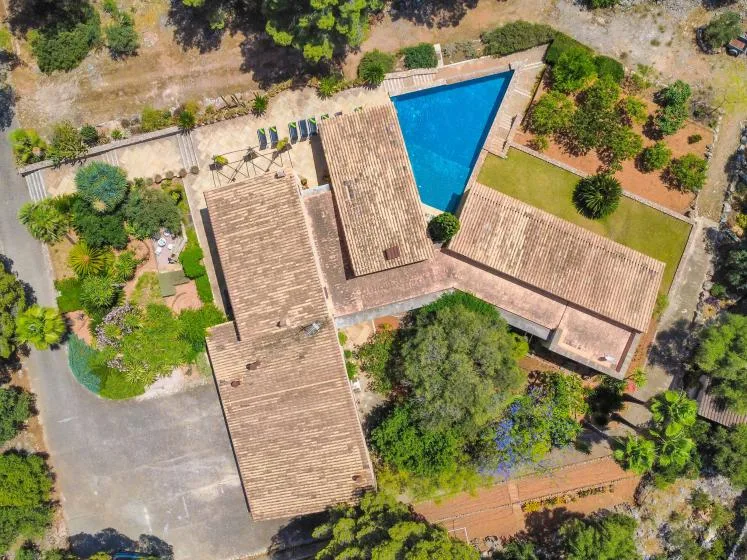 An aerial view of a tiled-roof house beside a blue swimming pool.