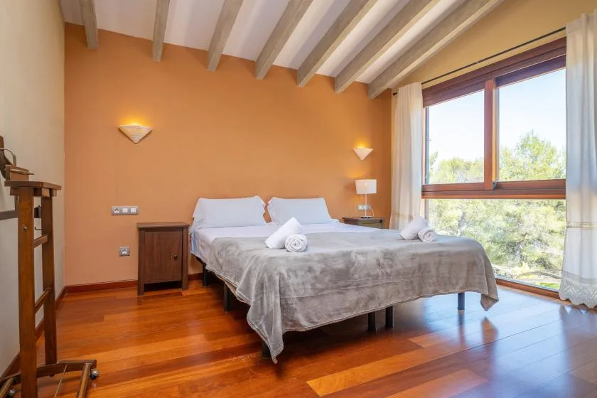 A bedroom with a double bed beside a large window.