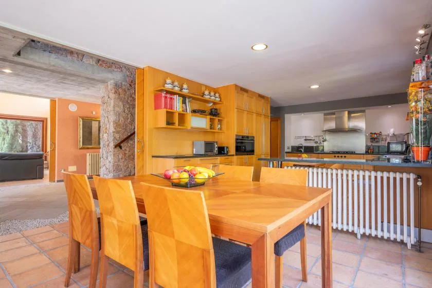 A dining area with a wooden table and chairs opens onto a kitchen.