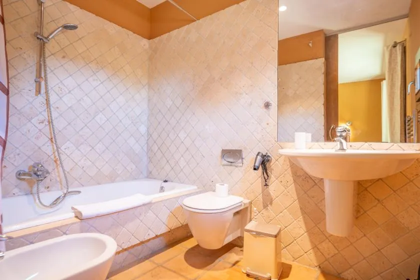 A tiled bathroom with a bathtub, toilet, and sink.