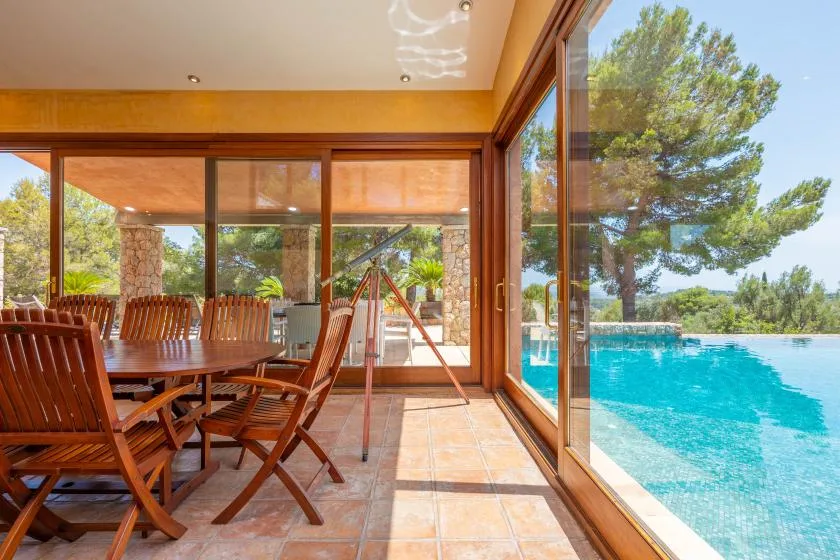 A glass-walled dining area opens onto a swimming pool and garden.