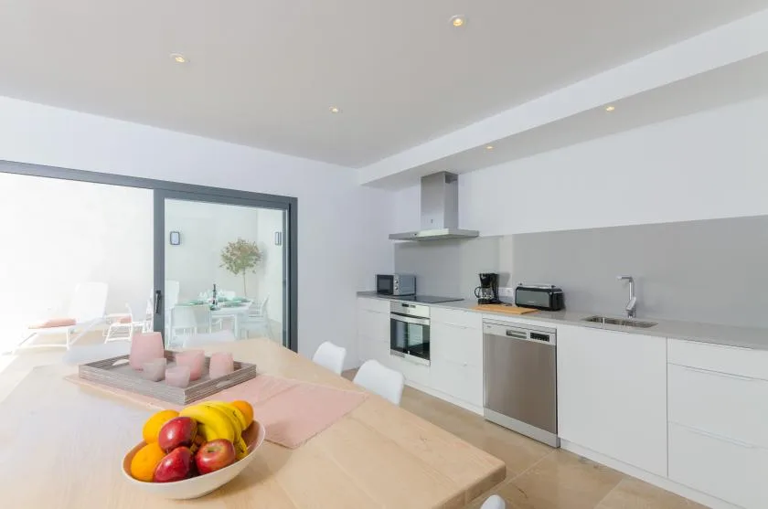 A bright open-plan kitchen and dining area with a table in the foreground.