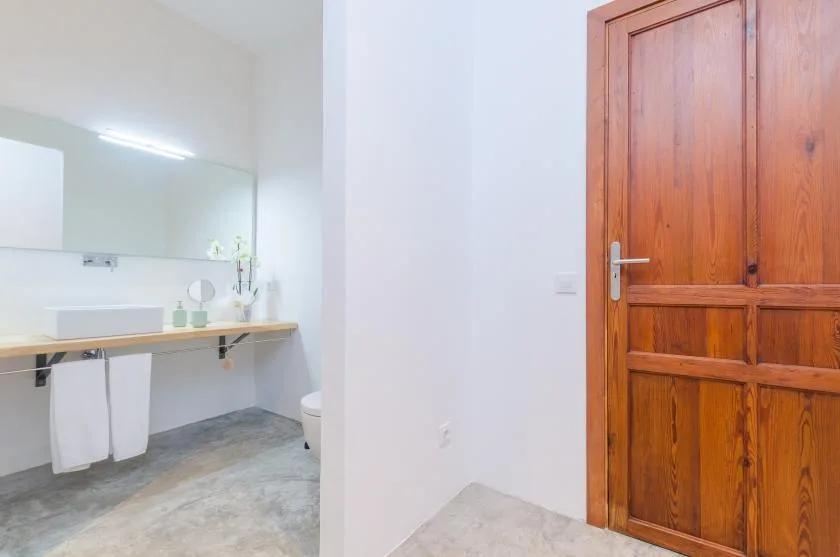A bathroom vanity area with a wall mirror and wooden door.