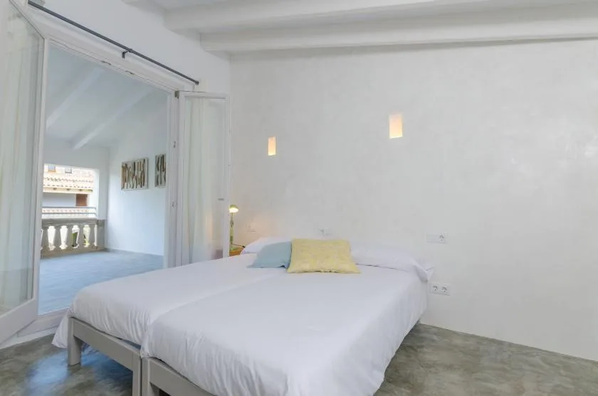 A bedroom with a white bed and pale walls.
