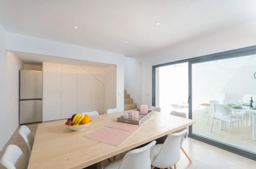 A bright dining area with a long table beside large glass doors.