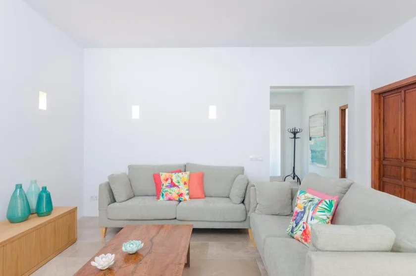 A bright living room with light seating and a wooden coffee table.