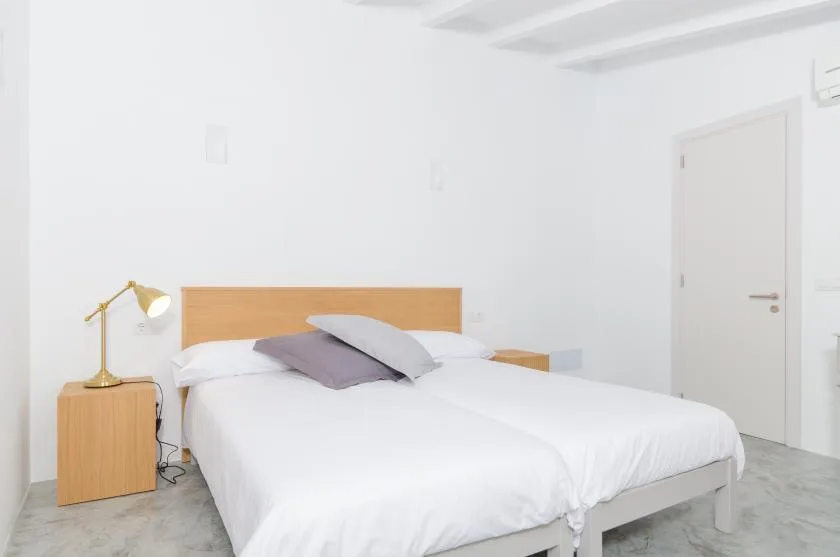 A bright bedroom with a neatly made bed and a bedside lamp.