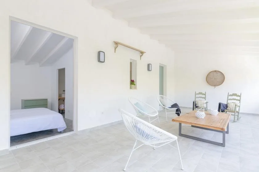 A bright indoor lounge with white seating and a wooden coffee table.