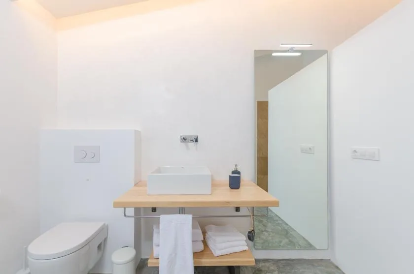 A bright bathroom with a vessel sink and a toilet.