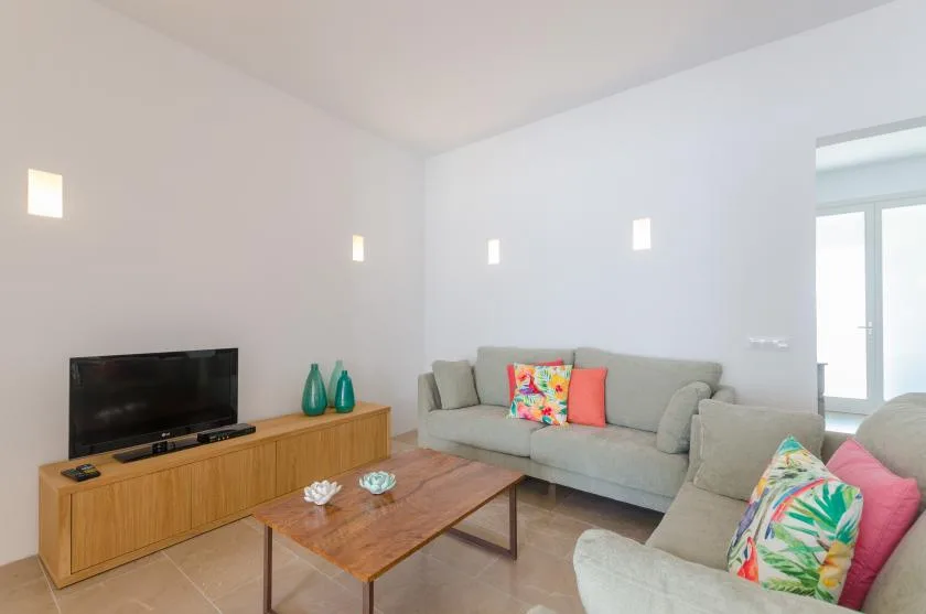 A bright living room with gray seating, colorful cushions, and a wooden coffee table.