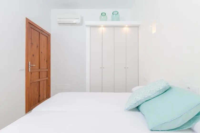 A bright bedroom with a white bed and built-in wardrobe.