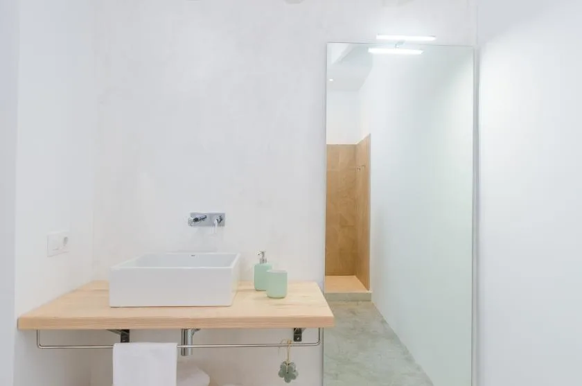 A bathroom vanity with a rectangular sink, mirror, and wall-mounted faucet.