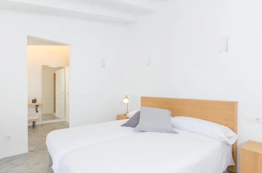 A bright bedroom with a neatly made bed and wooden headboard.