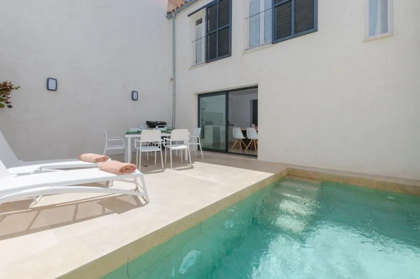 A courtyard pool beside a patio dining table and sliding glass doors.
