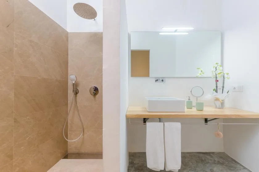 A bathroom vanity with a wide mirror beside a tiled shower.