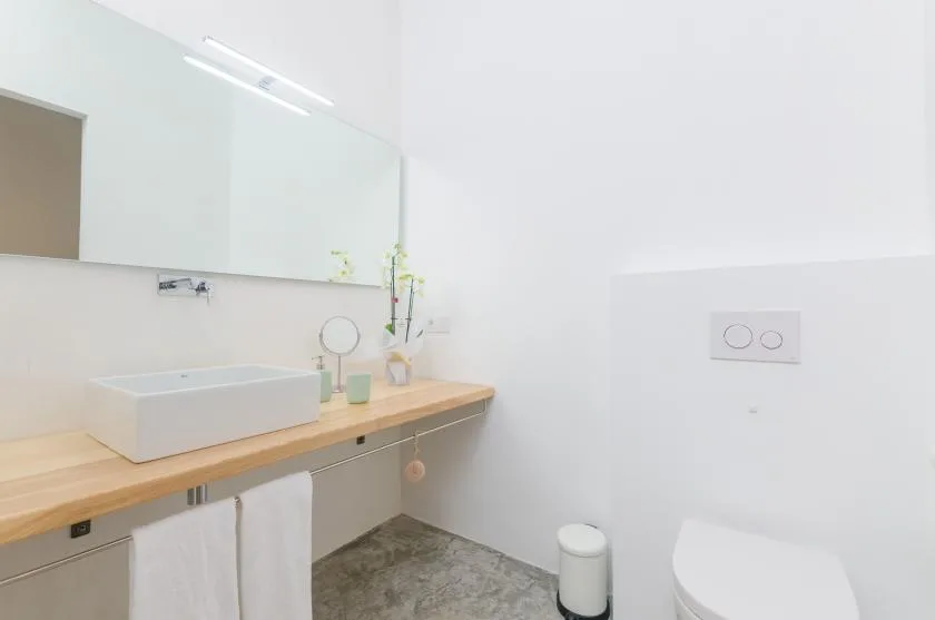 A bright bathroom with a long vanity, vessel sink, and wall mirror.