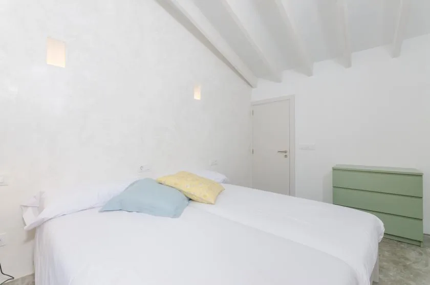 A bedroom with a neatly made bed and colored pillows.