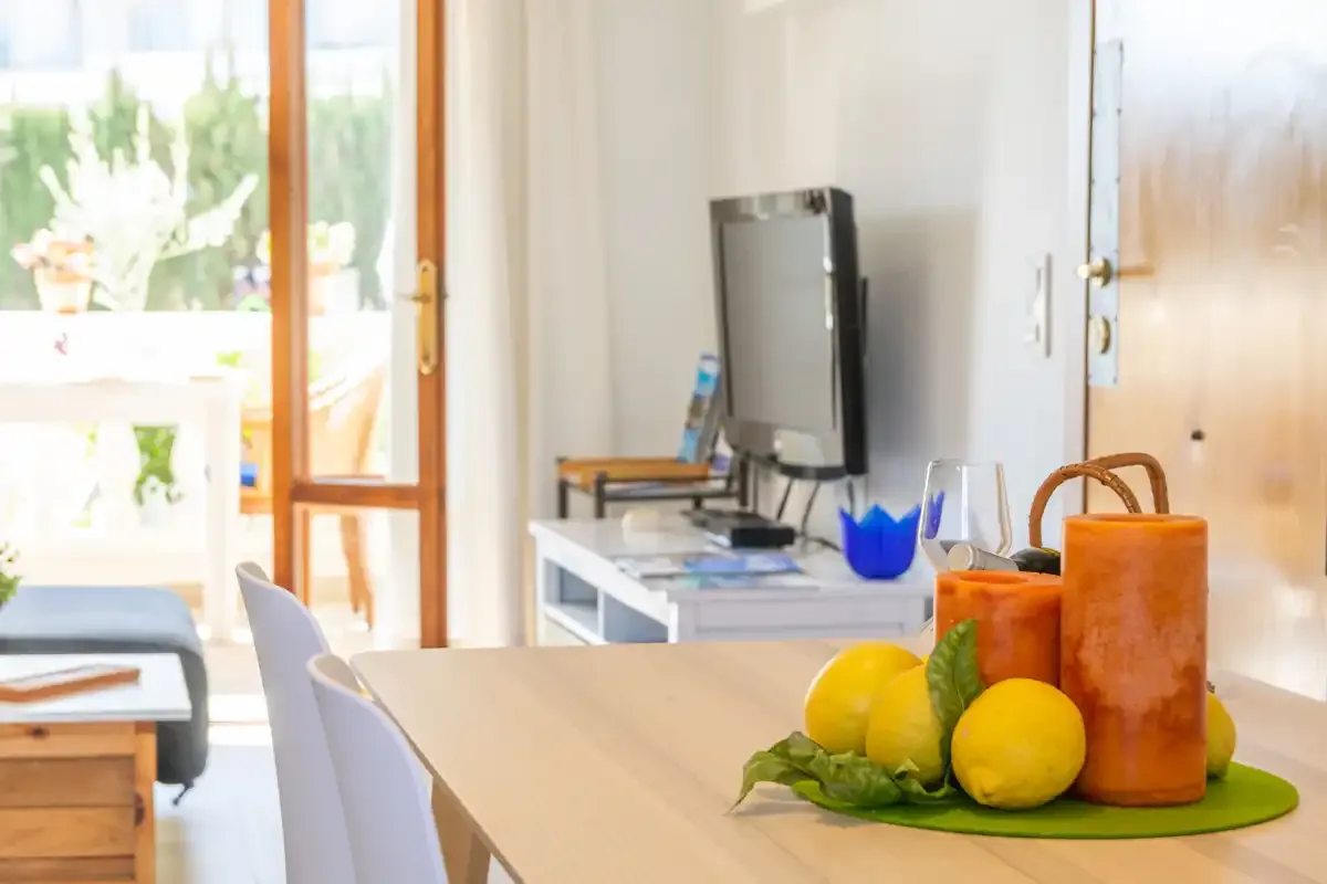 A bright dining area with a table, fruit, and a television.