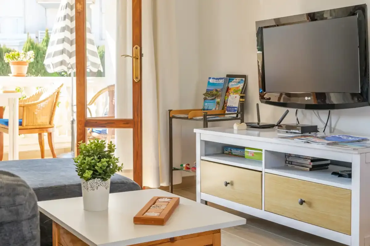 Living room with a television, low cabinet, and coffee table beside an open patio door.