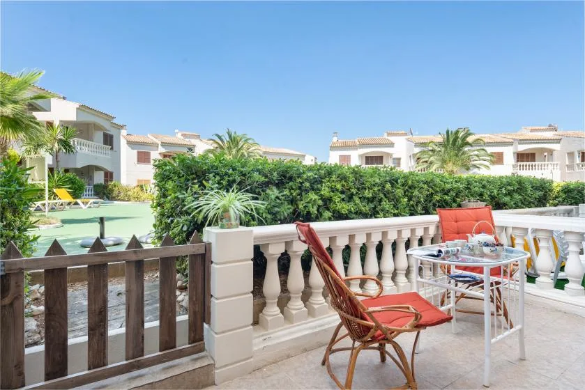 A sunny outdoor patio with seating overlooks a pool and landscaped grounds.