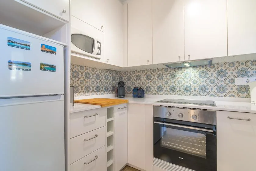 A bright kitchen with white cabinets, an oven, and patterned backsplash.