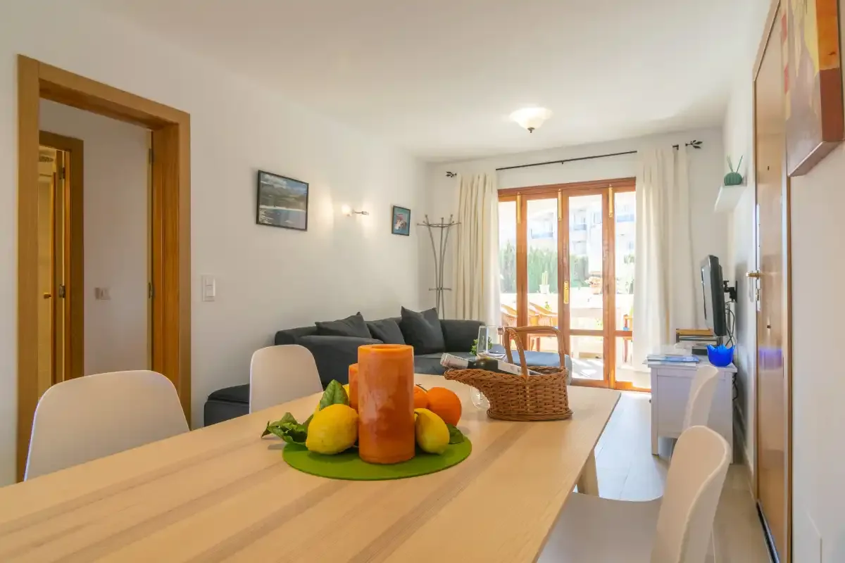 A bright living and dining area with a table, seating, and glass doors.