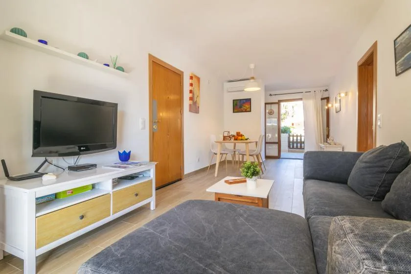 A living room with seating, a television, and a dining table near the balcony.