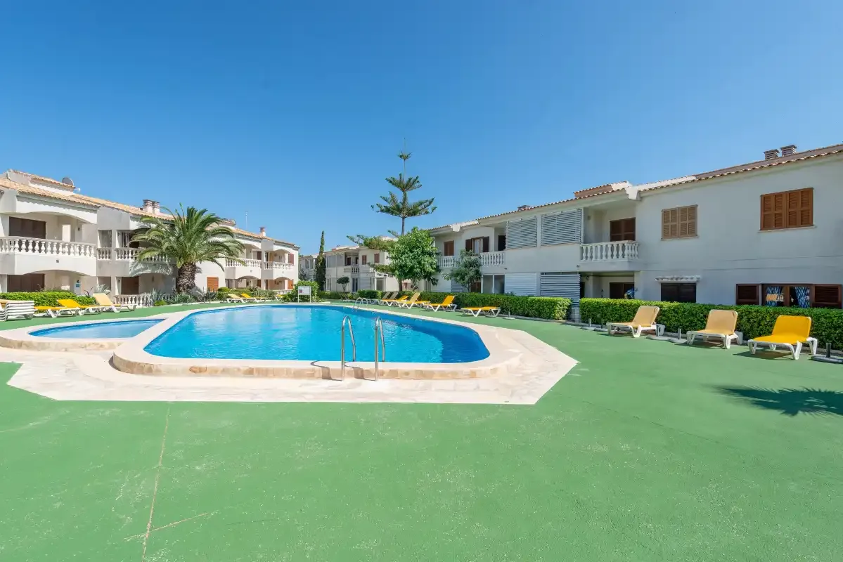 An outdoor swimming pool sits amid apartment buildings and lounge seating.