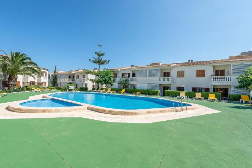 A swimming pool sits in a paved courtyard in front of low-rise buildings.