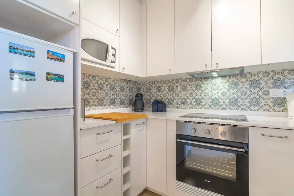 A bright kitchen with white cabinets and patterned tile backsplash.